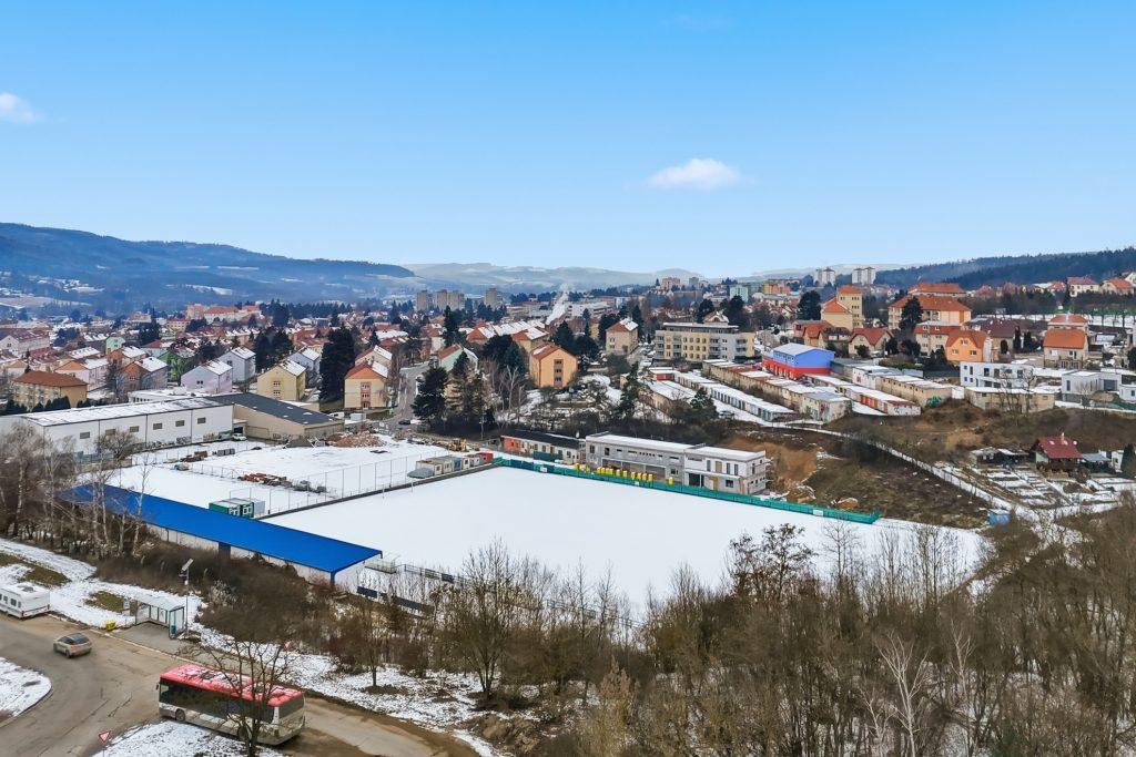 Širší dronový záběr ukazuje lokální kontext domu.